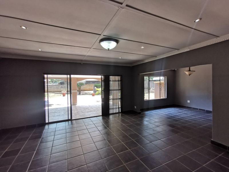 Spacious open-plan living area featuring dark tiled flooring, recessed lighting, and large sliding doors providing direct access to the outdoor patio.