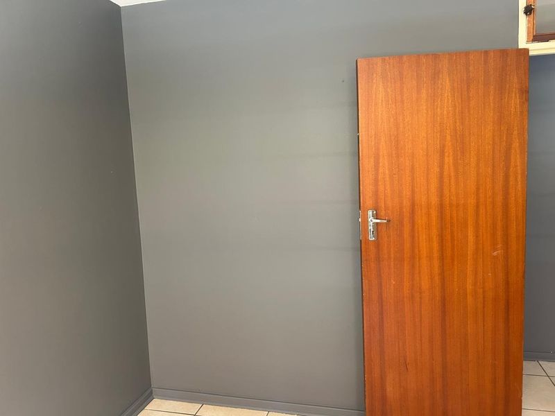 An empty room featuring dark grey painted walls, tiled flooring, and a solid wooden door.