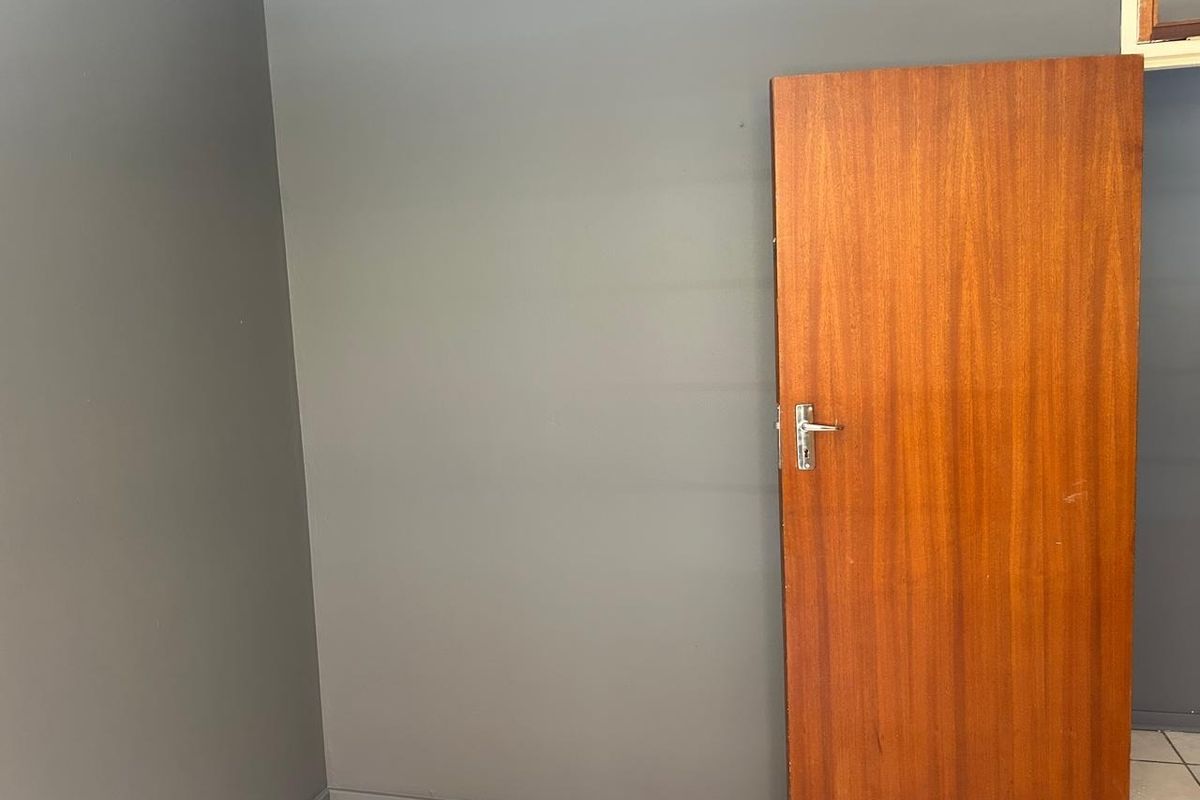 An empty room featuring dark grey painted walls, tiled flooring, and a solid wooden door.