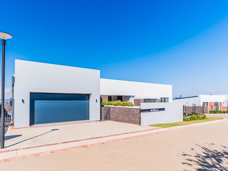 Modern single-story residential property featuring a clean architectural facade, double garage, and paved driveway in a well-maintained estate setting.
