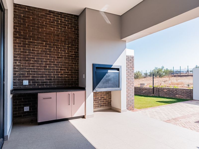 Covered patio featuring a built-in braai, granite countertop, and cabinetry, overlooking a private garden area.