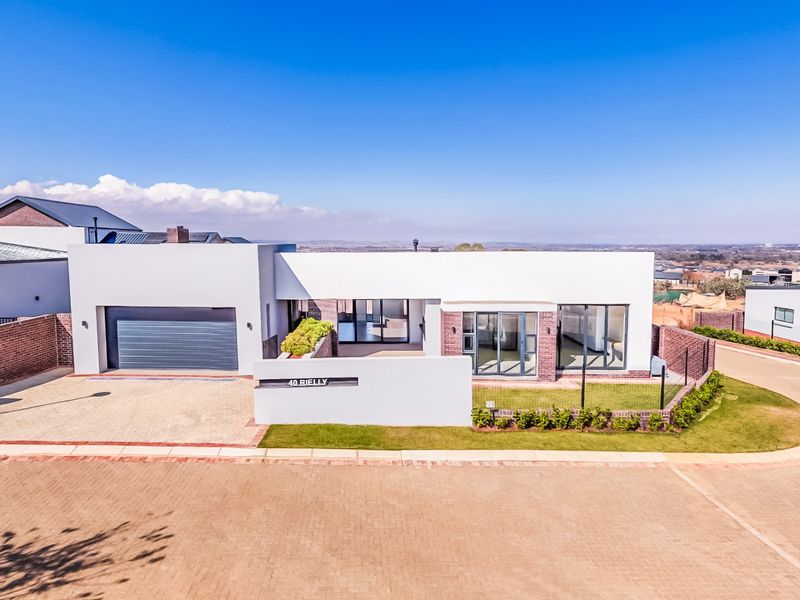 Modern single-story residential property featuring a clean white facade, double garage, paved driveway, and contemporary aluminium window and door frames.