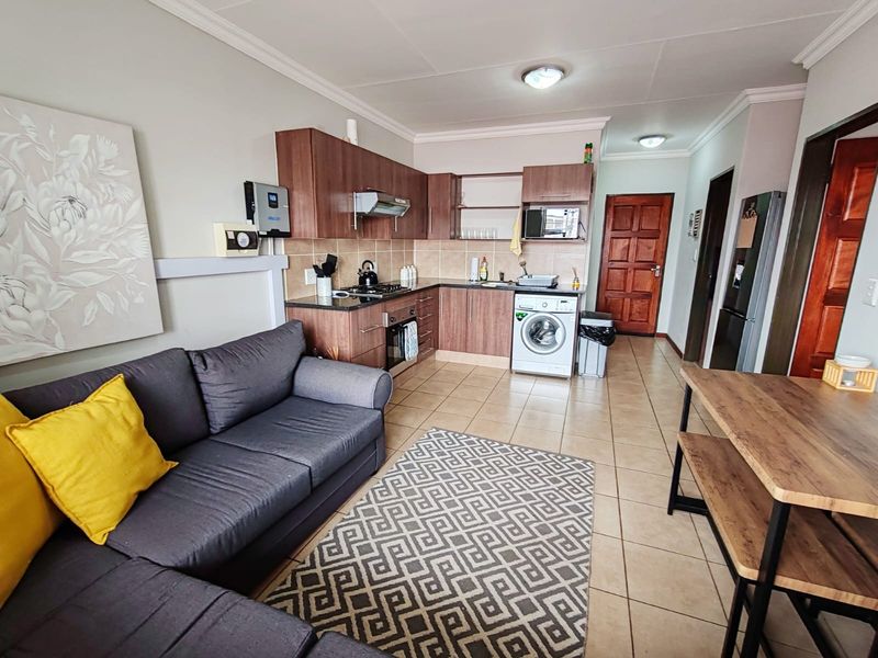 Open-plan living area featuring a functional kitchen with granite countertops, built-in cabinetry, and integrated appliances, seamlessly connected to the lounge space.