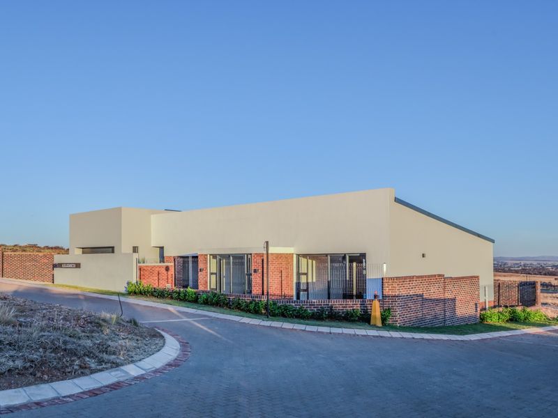 Modern single-story residence featuring a combination of brick and rendered finishes, set on a paved driveway with established garden borders.