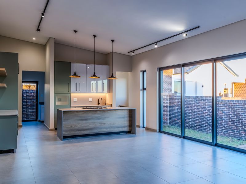 Modern open-plan kitchen featuring a central island, sleek cabinetry, integrated hob, and large sliding glass doors leading to the exterior.