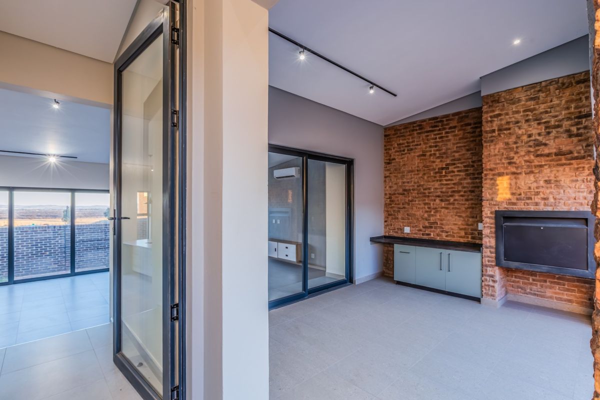 Modern living area featuring an exposed brick wall, built-in fireplace, sleek cabinetry, and large sliding glass doors leading to an outdoor space.
