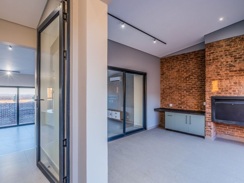 Modern living area featuring an exposed brick wall, built-in fireplace, sleek cabinetry, and large sliding glass doors leading to an outdoor space.