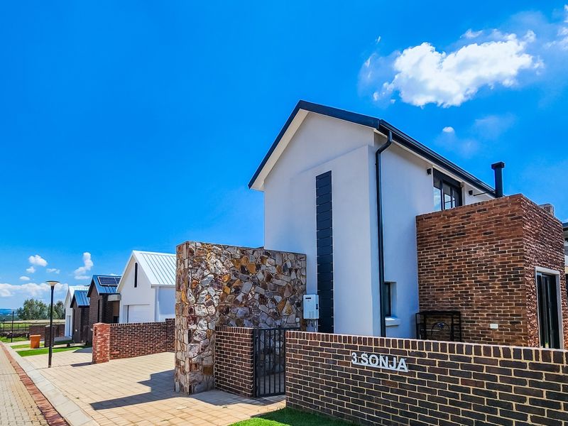 Modern residential facade featuring a combination of brick and stone cladding, paved driveway, and clean architectural lines in a well-maintained estate setting.