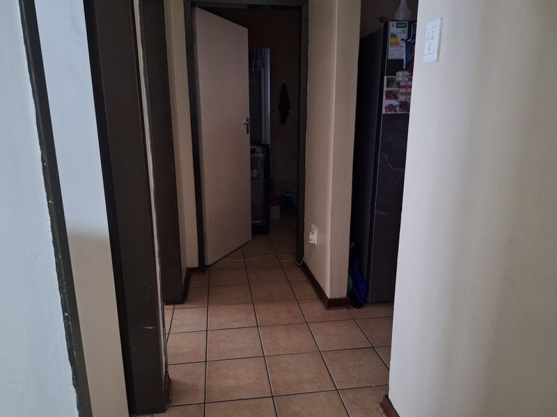 A functional hallway featuring tiled flooring and access to adjacent rooms, showing signs of wear and requiring cosmetic updates.
