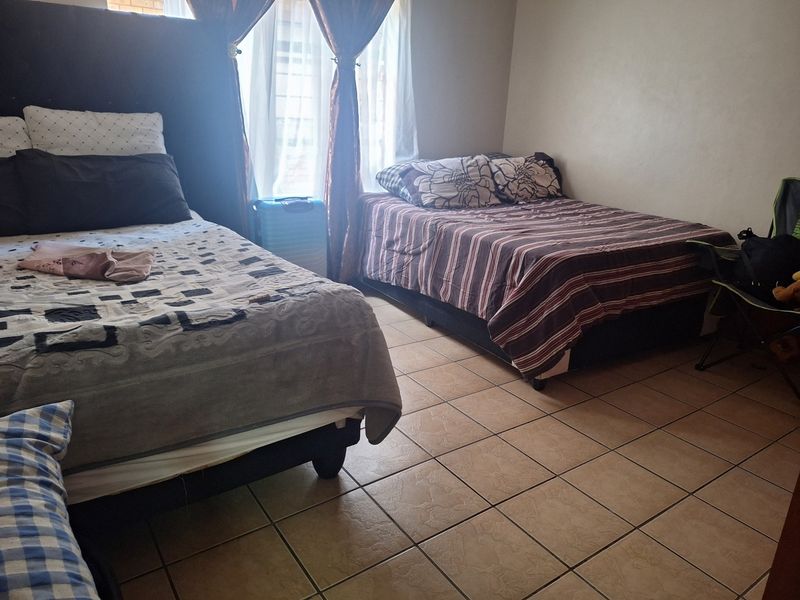 A bedroom featuring tiled flooring and a window, currently configured with multiple beds.