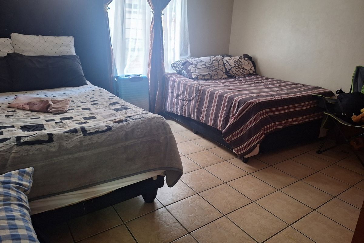 A bedroom featuring tiled flooring and a window, currently configured with multiple beds.