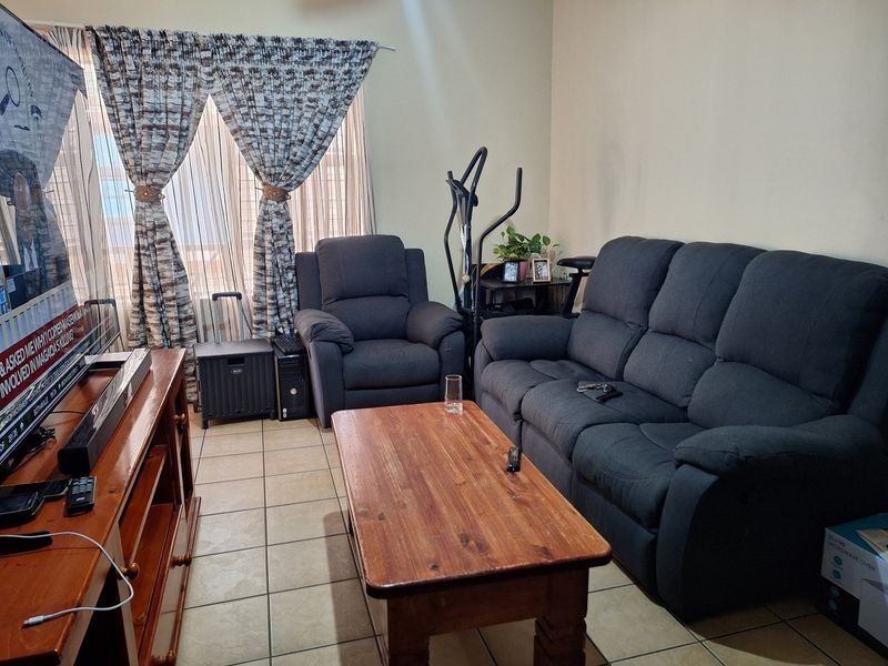 A functional living room featuring ceramic floor tiles and large windows with curtain tracks, providing a neutral base for potential interior updates.