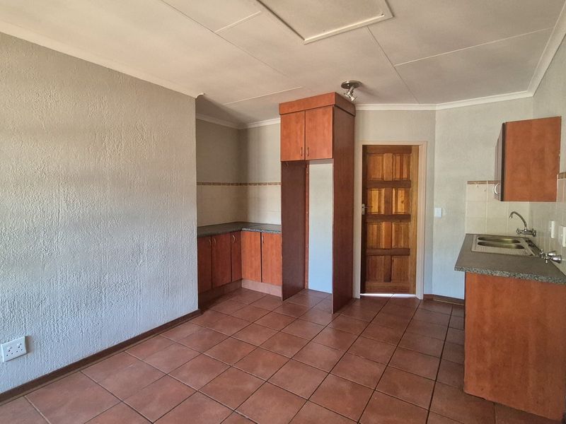 An empty kitchen featuring built-in wooden cabinetry, laminate countertops, a double bowl sink, and tiled flooring, offering a functional space ready for updates.