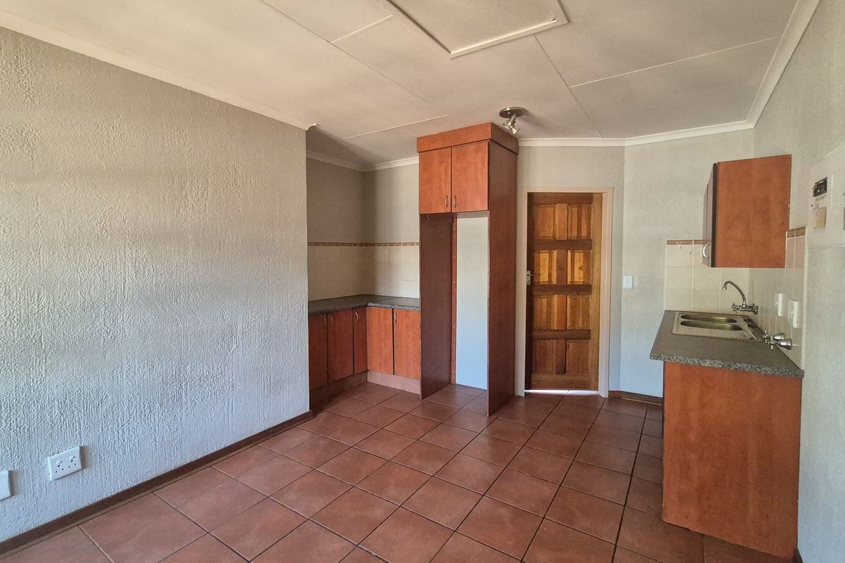 An empty kitchen featuring built-in wooden cabinetry, laminate countertops, a double bowl sink, and tiled flooring, offering a functional space ready for updates.