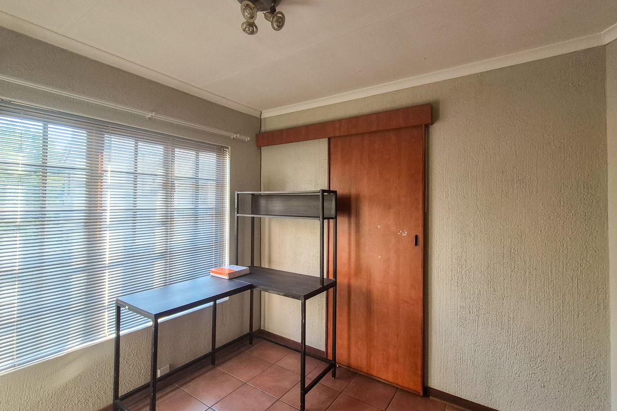 A bedroom featuring tiled flooring, a sliding door, and venetian blinds, offering a functional space with potential for cosmetic updates.