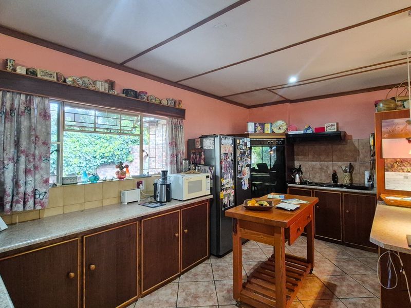A functional kitchen featuring dark wood cabinetry, tiled backsplash, and tiled flooring, offering a traditional layout with ample counter space.