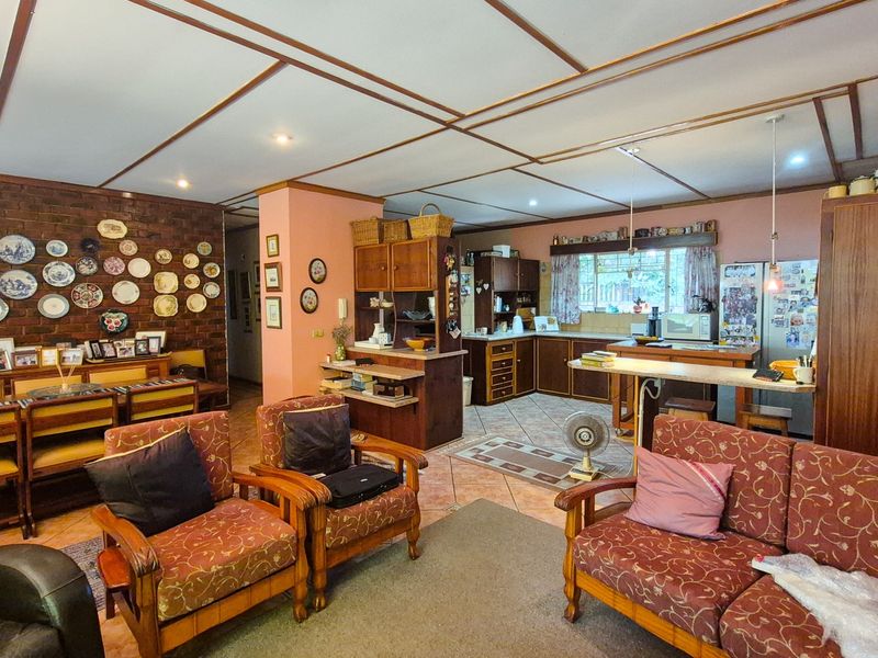 Spacious open-plan living and kitchen area featuring exposed brickwork, tiled flooring, and a functional kitchen layout with built-in cabinetry.
