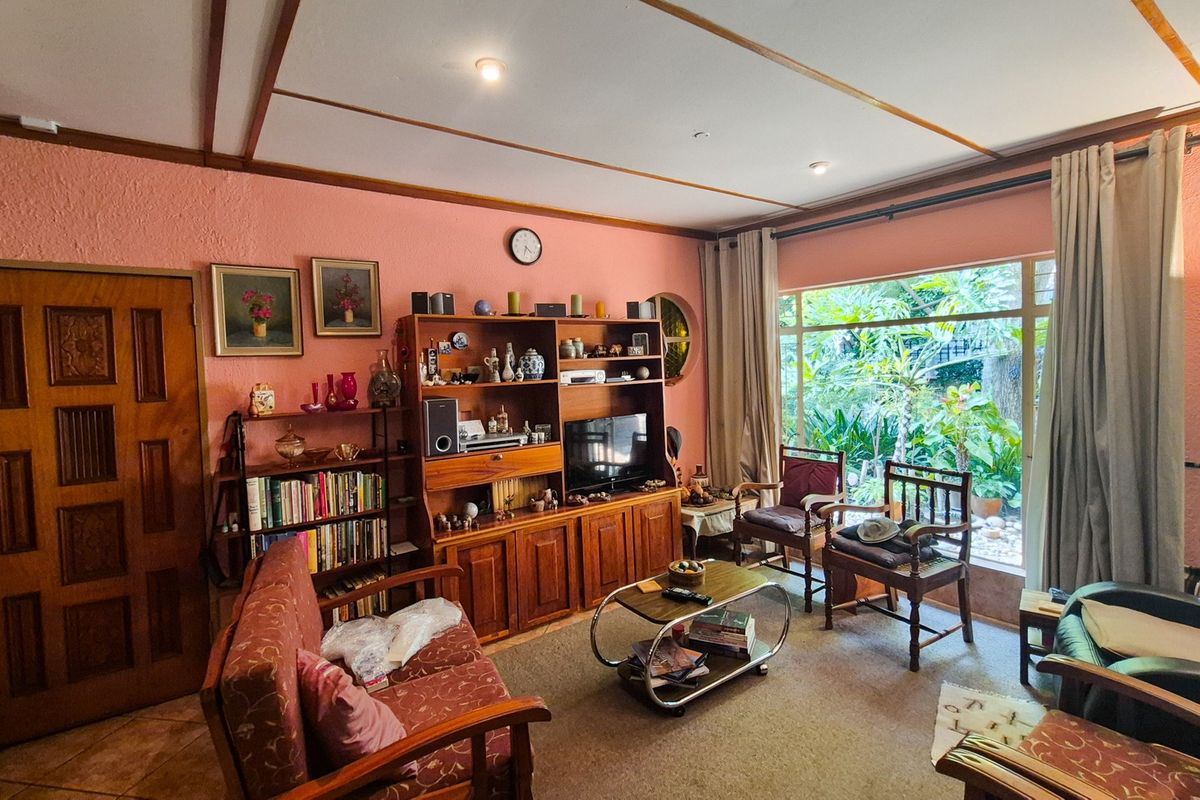 A comfortable living room featuring a large picture window with garden views, timber-panelled ceiling, and recessed lighting, offering a warm and inviting atmosphere.