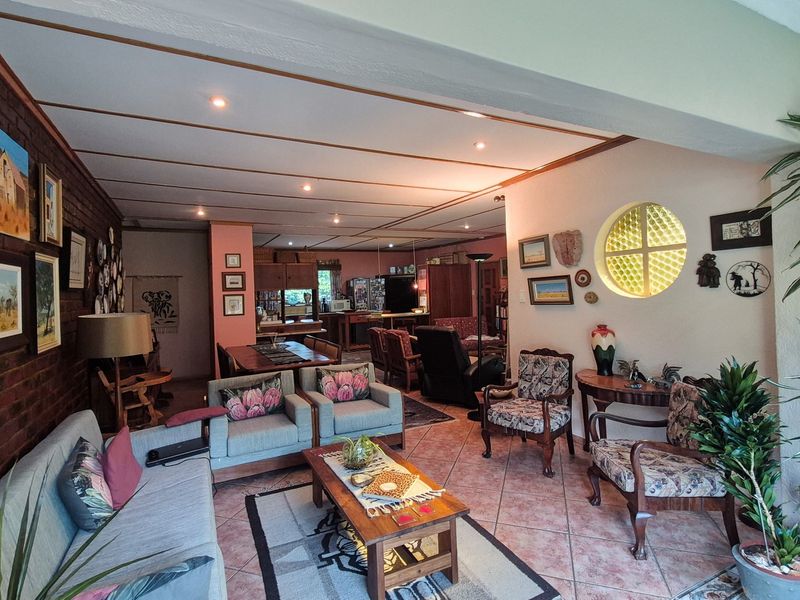 Spacious open-plan living and dining area featuring an exposed brick feature wall, circular glass block window, and tiled flooring throughout.