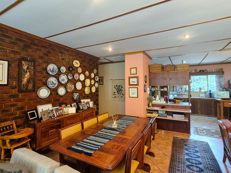 Open-plan living and dining area featuring an exposed brick feature wall, tiled flooring, and an adjoining kitchen with built-in cabinetry.