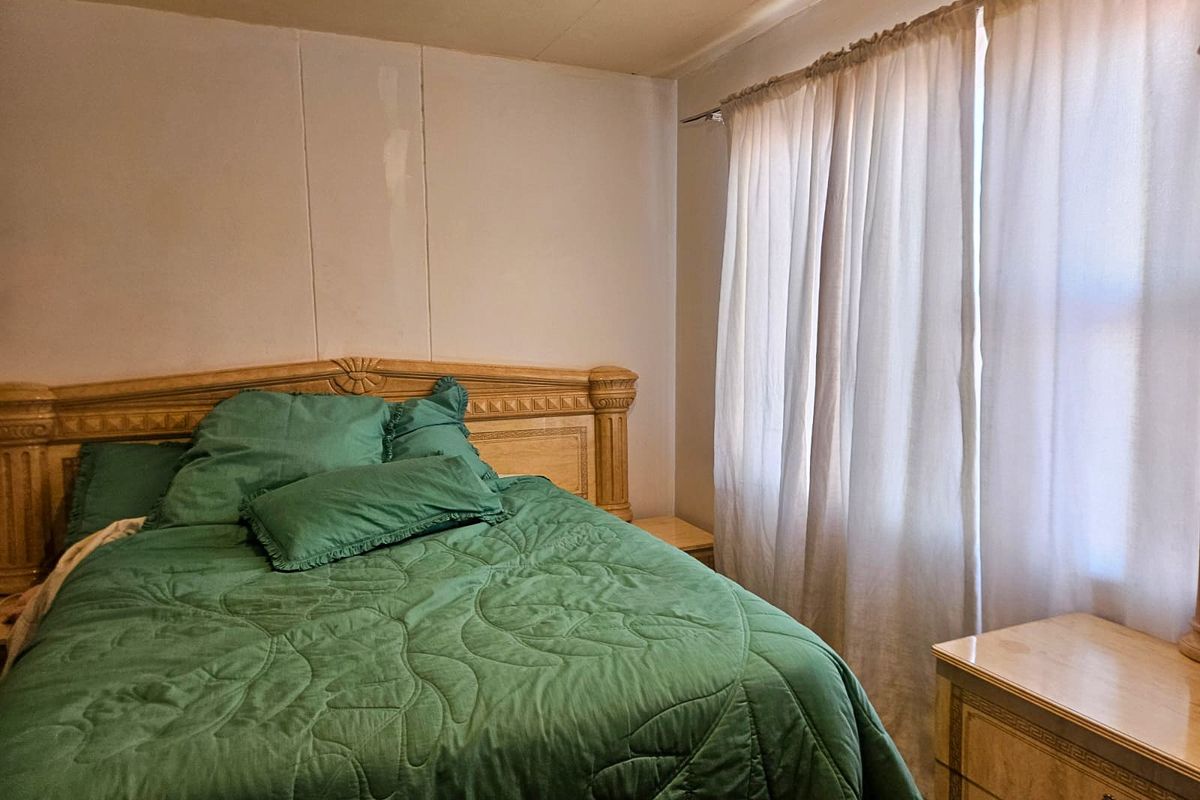 A bedroom featuring wall paneling and window treatments, requiring cosmetic updates to improve the overall aesthetic and finish quality.