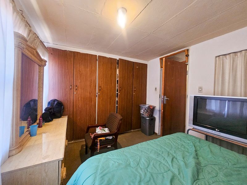 A bedroom featuring built-in wooden cupboards and carpeted flooring, offering a functional space with potential for modernization.