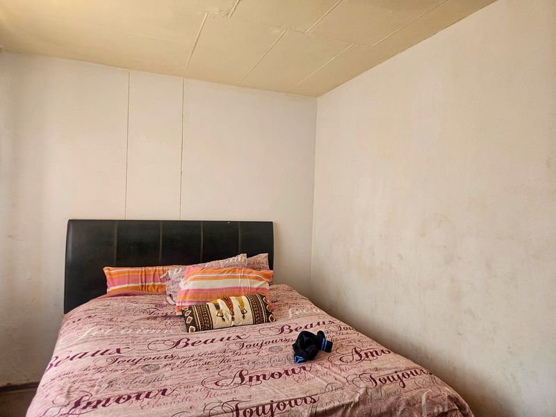 A bedroom featuring plain walls with visible staining and a panelled ceiling in need of maintenance.