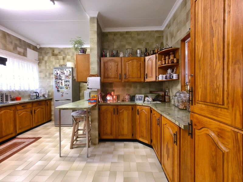 A spacious kitchen featuring traditional wooden cabinetry, tiled backsplash, and a built-in breakfast bar, offering a functional layout with ample storage space.