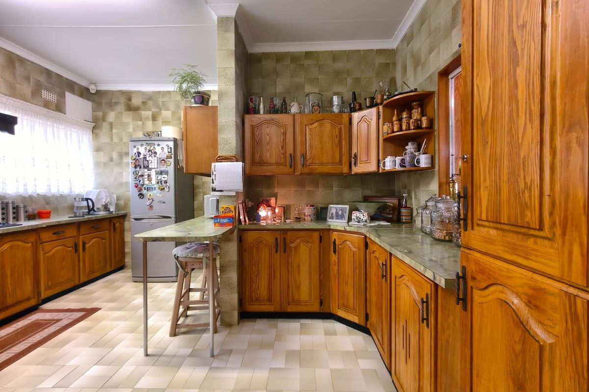A spacious kitchen featuring traditional wooden cabinetry, tiled backsplash, and a built-in breakfast bar, offering a functional layout with ample storage space.