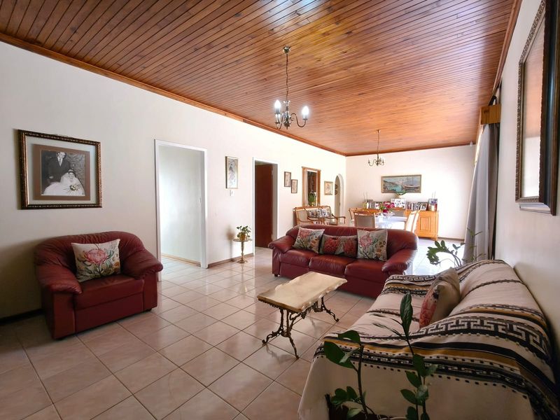 Spacious open-plan living and dining area featuring a warm timber-clad ceiling and neutral ceramic floor tiles throughout.