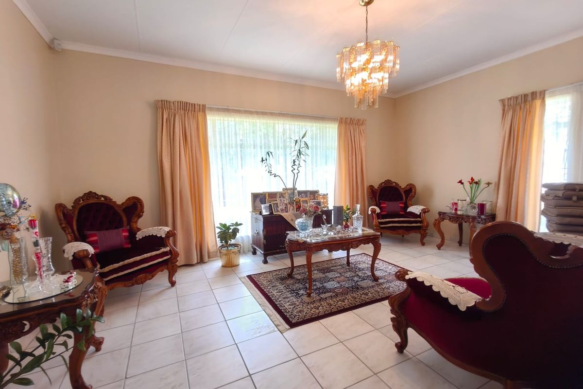 A formal living room featuring ceramic floor tiles, a decorative crystal chandelier, and coved ceiling details, offering a classic and well-maintained space.