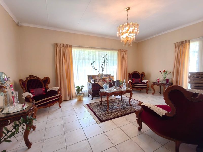 A formal living room featuring ceramic floor tiles, a decorative crystal chandelier, and coved ceiling details, offering a classic and well-maintained space.