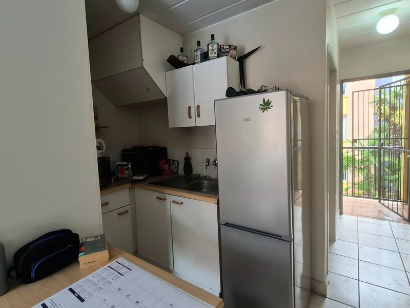 Compact kitchen area featuring built-in cabinetry, a stainless steel sink, and tiled flooring, with direct access to an outdoor balcony area.