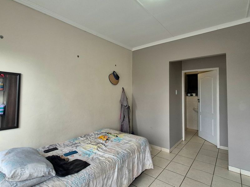 A bedroom featuring tiled flooring and coved ceilings, with access to an adjoining room through a standard internal door.