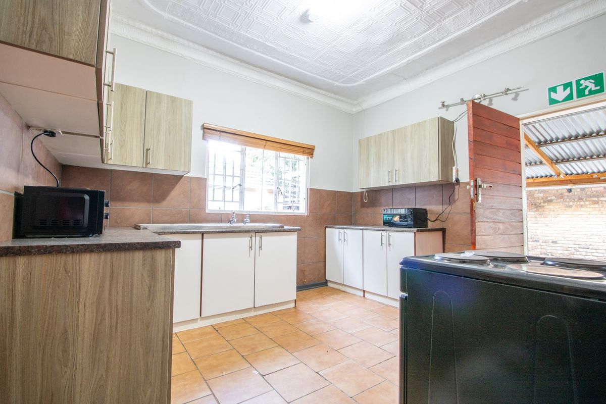 Functional kitchen featuring laminate cabinetry, tiled backsplash, and tiled flooring, with direct access to an outdoor area.