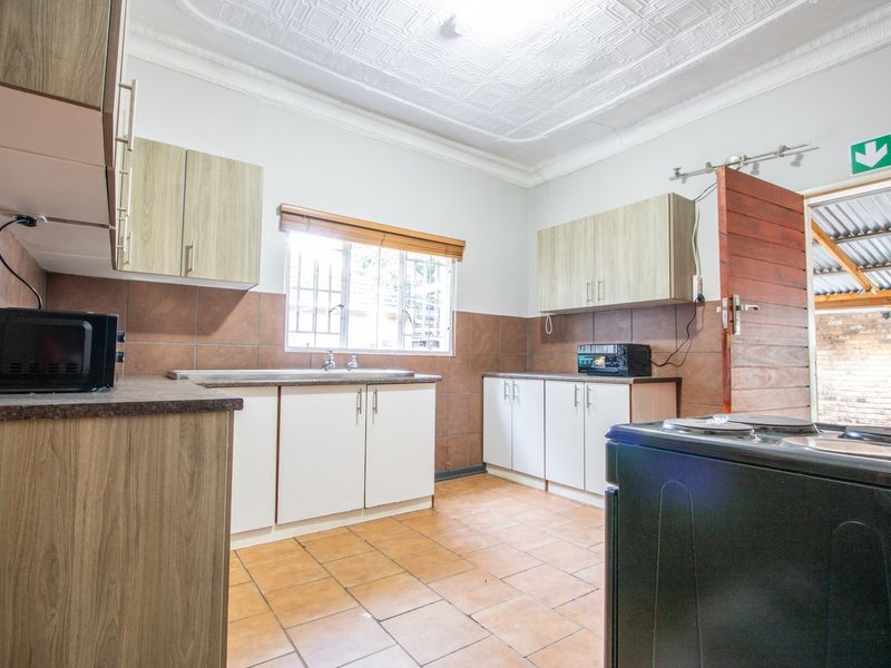 Functional kitchen featuring laminate cabinetry, tiled backsplash, and tiled flooring, with direct access to an outdoor area.
