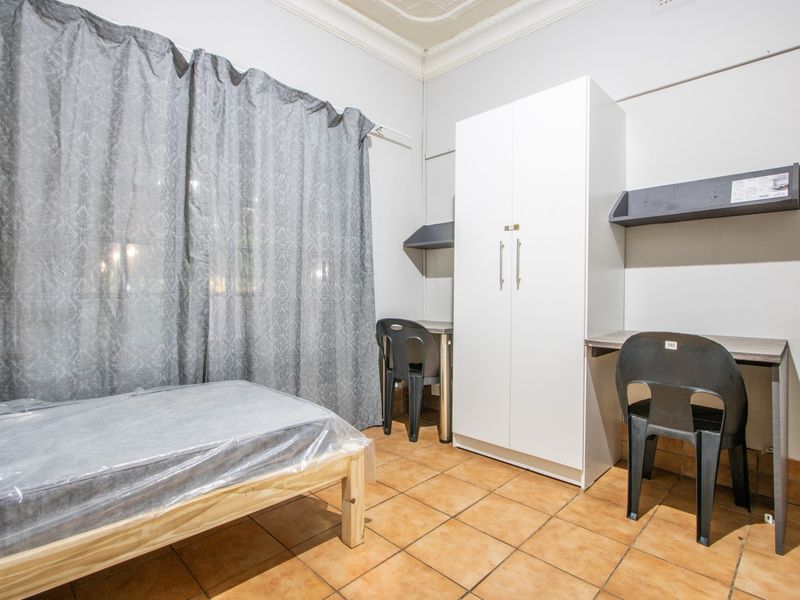 A functional bedroom featuring tiled flooring, built-in wardrobe, and integrated desk space with decorative ceiling detailing.