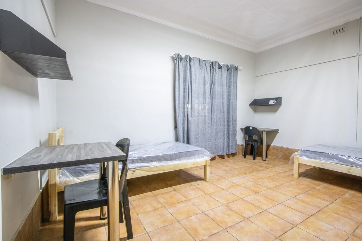 A functional bedroom featuring ceramic tile flooring, coved ceilings, and built-in shelving, providing a basic living space.