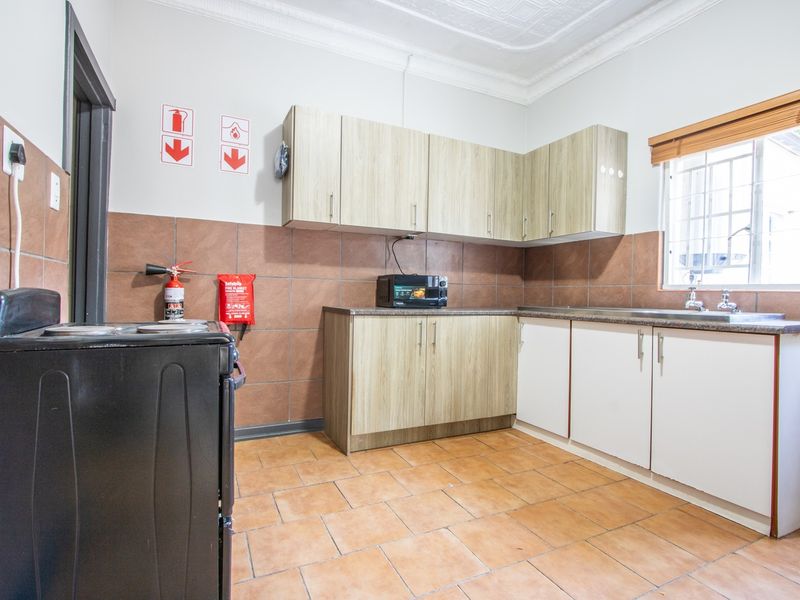 Functional kitchen featuring laminate cabinetry, ceramic tile backsplash, tiled flooring, and a stainless steel sink with a window view.