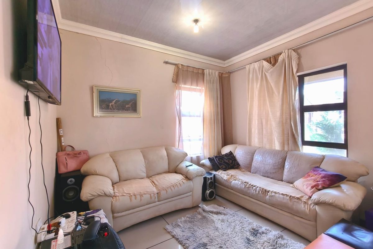 A living room featuring tiled flooring and cornicing, currently showing visible wall cracks that may require maintenance.