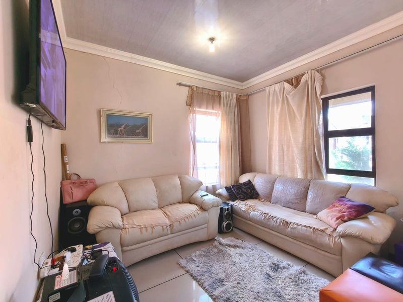 A living room featuring tiled flooring and cornicing, currently showing visible wall cracks that may require maintenance.