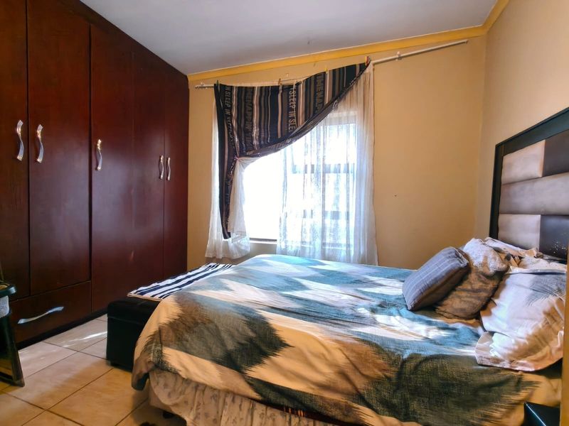 A bedroom featuring built-in wooden cupboards and tiled flooring, offering a functional space with potential for cosmetic updates.