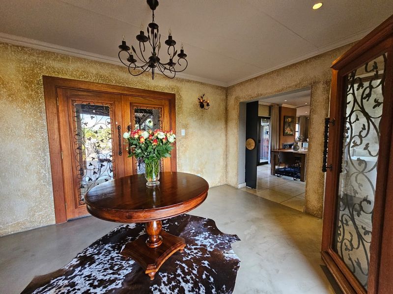 Welcoming entrance hall featuring polished concrete floors, textured walls, and elegant wrought iron double doors leading to the main living areas.