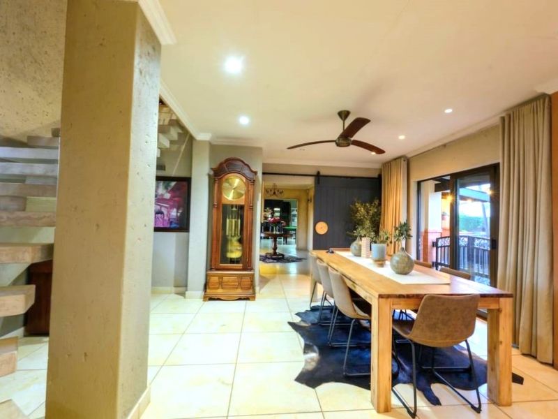Spacious dining area featuring tiled flooring, a modern floating staircase, and sliding glass doors leading to an outdoor space.