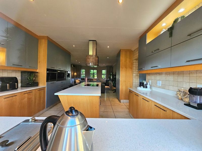 Spacious open-plan kitchen featuring a central island, modern cabinetry, stone countertops, and integrated appliances, flowing seamlessly into the living area.