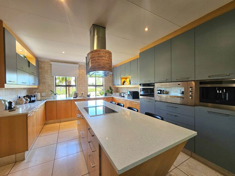 Modern kitchen featuring a large central island with stone countertops, integrated appliances, ample cabinetry, and high-quality finishes throughout.