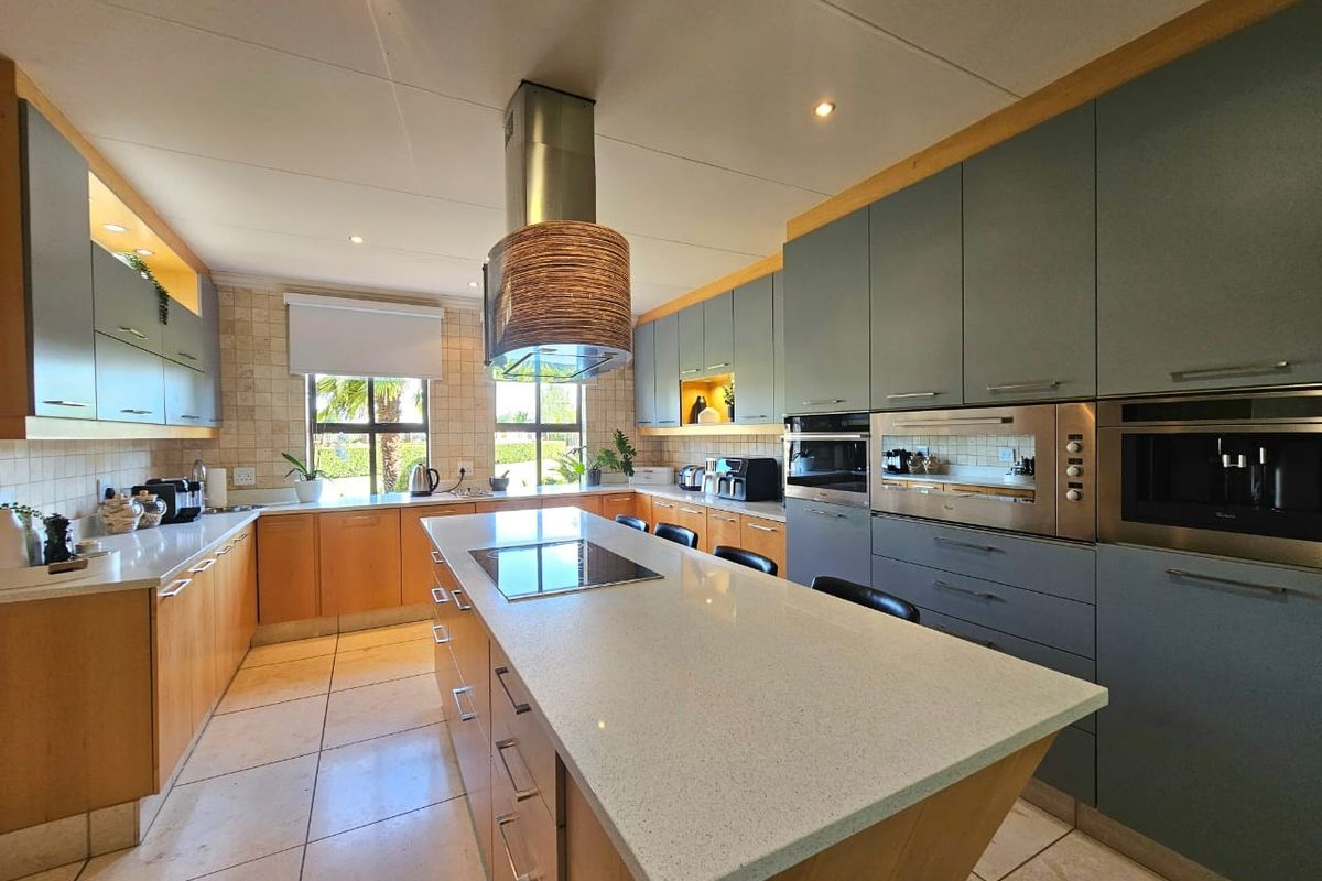 Modern kitchen featuring a large central island with stone countertops, integrated appliances, ample cabinetry, and high-quality finishes throughout.