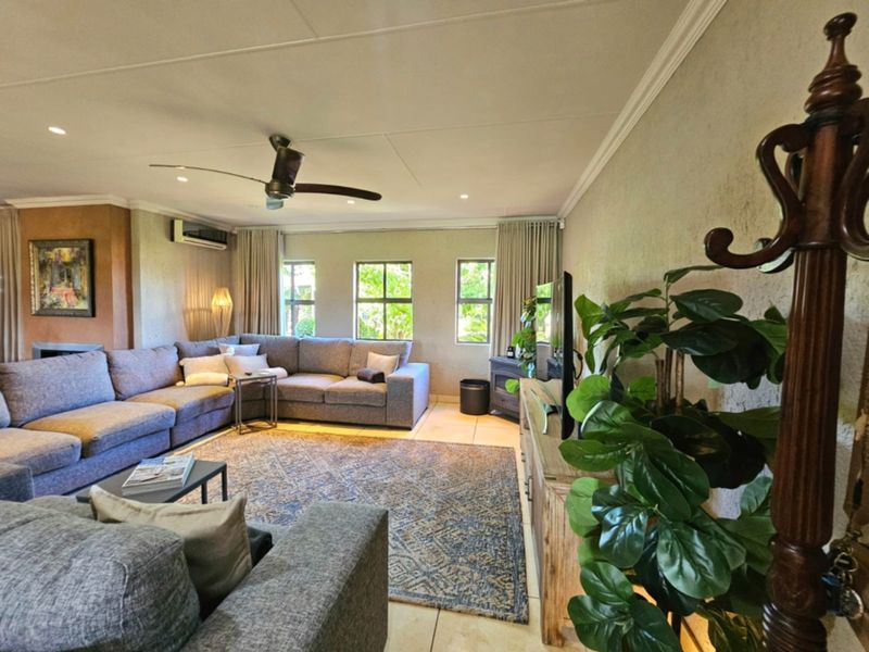 A spacious living room featuring tiled flooring, recessed lighting, a ceiling fan, and a built-in fireplace, offering a comfortable and well-maintained living space.
