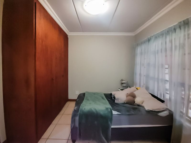 A bedroom featuring tiled flooring, a large built-in wooden wardrobe, and a ceiling light fixture.