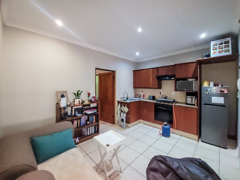 Open-plan kitchen and living area featuring wooden cabinetry, built-in oven, gas hob, and tiled flooring throughout.